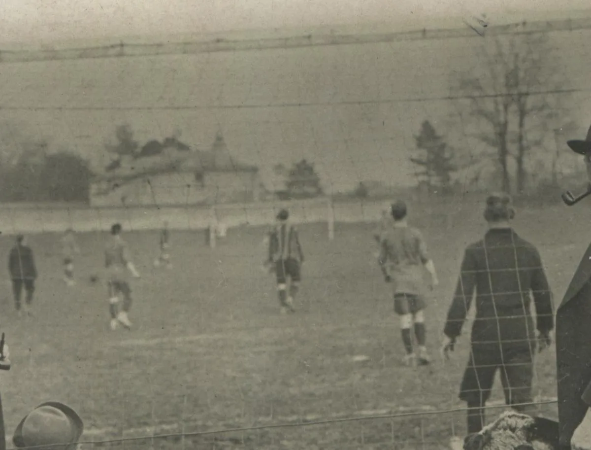 Black and white photograph of an early Andover football match seen through the goal net